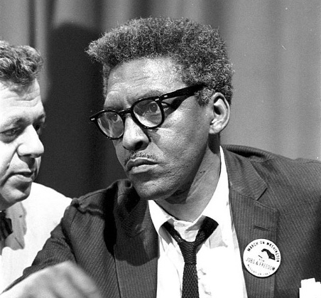 A man sits at a table as another man turns to him.